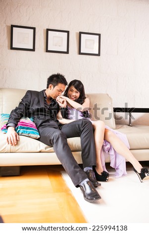Bride and groom happy sweet sitting on the sofa with on wall background.