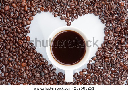 Heap of coffee beans with coffee cup in white heart. / love in coffee heart blank, isolated on white background.