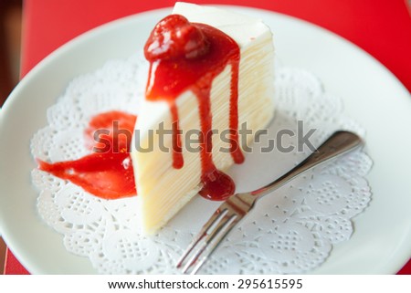 Strawberry cheese cake on white plate and silverware red backgroud