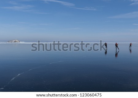 Three ice skaters on a big lake with crystal clear ice. VÃ?Â¤ttern, VÃ?Â¤stra GÃ?Â¶taland, Sweden.