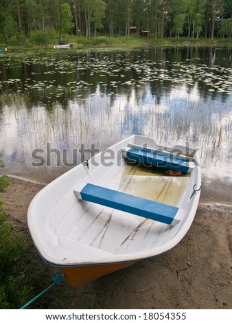A small open boat on the shore of a small lake.