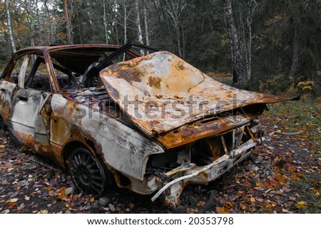 stock photo A rusty old car wreck in a forest