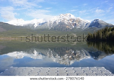 View of grey plastic floating pier and reflection of Pyramid mountain in Pyramid Lake in Jasper National Park, Canada, UNESCO World Heritage site
