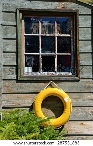Bright Yellow Life Saver on Faded Wooden Wall with Window Panes