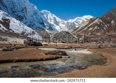 Clear water of mountain river and snowy mountain, trekking in Everest region, Nepal