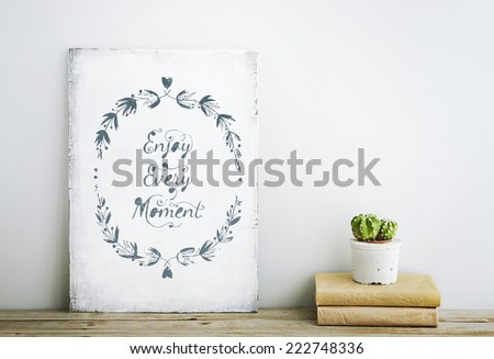 motivational inspirational poster quote ENJOY EVERY MOMENT on the white wall. American or Scandinavian style room interior.