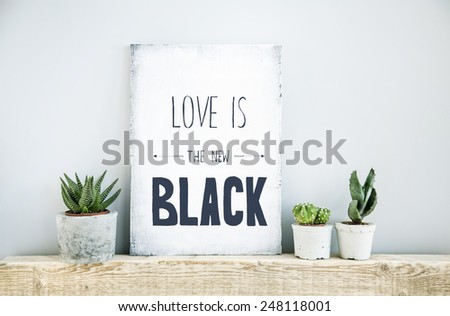 scandinavian or american style room interior with painted frame - poster quote LOVE IS THE NEW BLACK and three succulents in diy concrete pot background for text