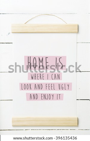 Scandinavian hipster interior design.  Wooden frame with funny poster quotes HOME IS WHERE I CAN BE UGLY AND ENJOY IT
