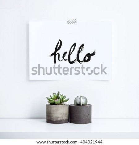 Scandinavian interior design. Hipster motivational set with  succulent in concrete planter. Note paper on the wall with quote HELLO