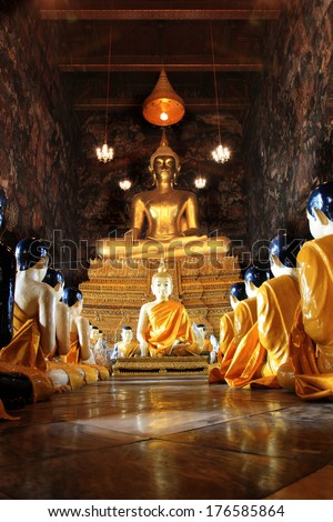 Buddha statues and monk statues sitting in row , Wat Suthat, Thailand, Statue in Buddhist Thailand temple or wat, are public domain or treasure of Buddhism no restrict in copy or use.