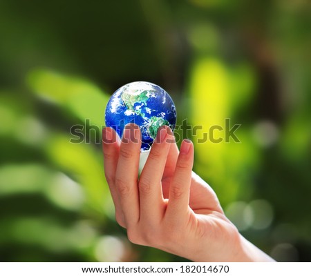 Globe in human hand against natural background, Elements of this image furnished by NASA