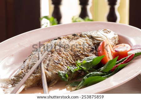 Fried pickled fish , tomato and chili served with fresh vegetable on dish