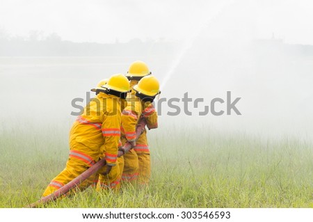 Group of firefighters advance forward putting out a fire.