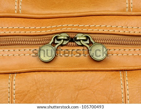 close-up of two zip fastenings on leather luggage