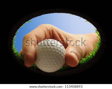 hand taking a golf ball out of a golf hole seen from below