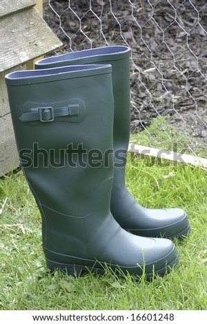 a pair of green rubber boots next to a chicken coop