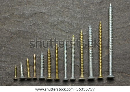 positive graph using various sized screws as bar charts on slate background