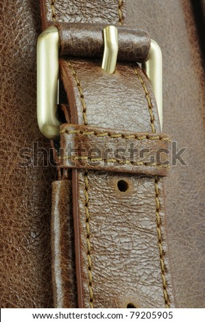 gold buckle on brown leather handbag strap