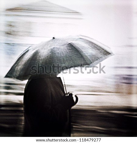 Man in a rain walking with umbrella. Unrecognizable person in motion blur.