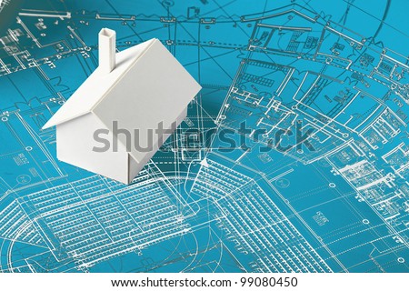 Small simple white model house on blueprints