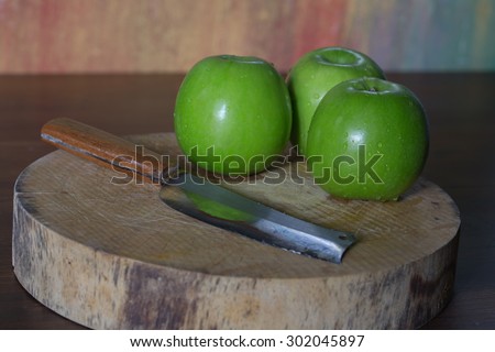 Green apple on a wood cutting board and knife Stripping.