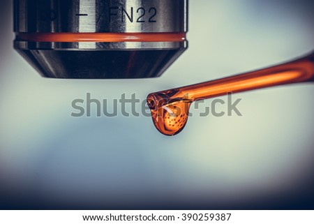 Macro of a pipette adding a drop of fluid to one of several cylindrical phials Vintage