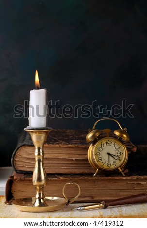 Candle with books and an alarm clock
