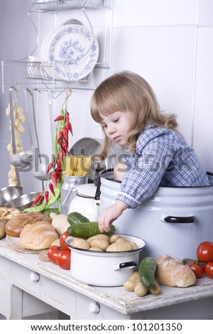 the beautiful little girl sits in a big pan on a table not to kitchen