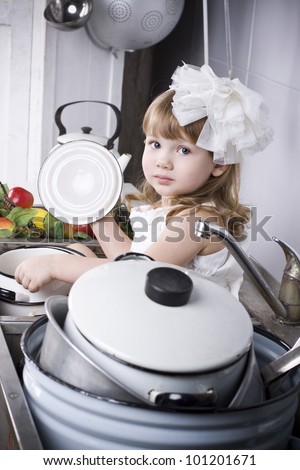 the beautiful little girl washes the dishes