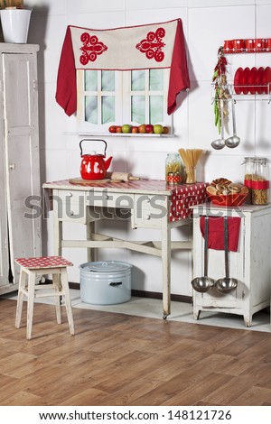 red and white kitchen with old furniture, food and utensils in a country house