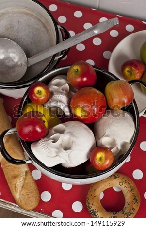 Three skulls in a pan with apples on a table in the kitchen