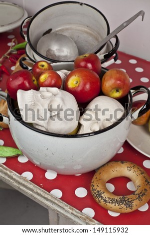 Three skulls in a pan with apples on a table in the kitchen