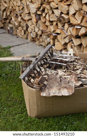 box of bark and wood chips on the grass against the woodpile