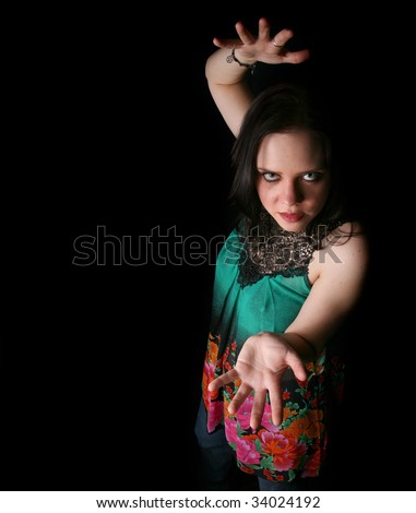 Mystic Woman in Bright Colored Top Holding Up Empty Hand  on Black Background with Copy Space to Left