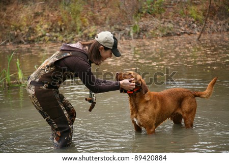 Woman Duck Hunter petting Labrador Retriever in Pond