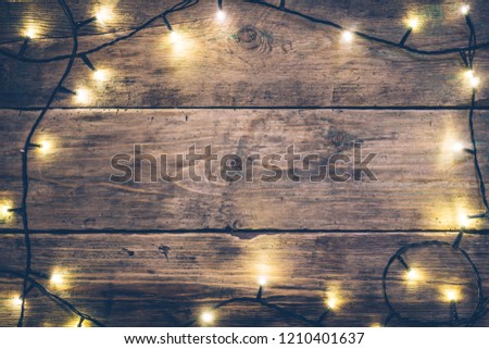 Christmas lights frame. Christmas wooden rustic background with (decorated) christmas lights. Copy space. Top view. Christmas mood, comfort.