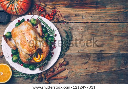 Thanksgiving roasted chicken with Brussels sprouts and spices on a rustic wooden table. Thanksgiving dinner or fall dinner concept background with autumn leaves. Thanksgiving table setting background.