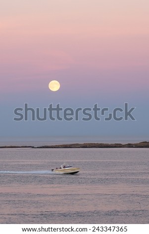 Big full moon is rising above the sea island in the Strait of Georgia at dusk