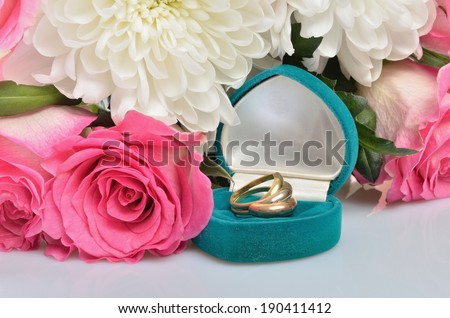 A small gift box with jewelry ring and a bouquet of flowers