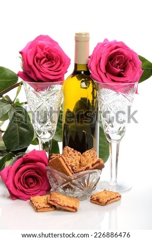 Crystal glasses, a bottle of wine, cookies and a bouquet of roses in a still life
