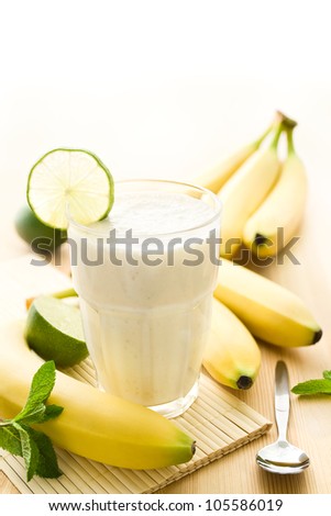 Banana milkshake or smoothie with bananas on wood
