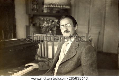 USSR, Russia, - CIRCA 1948: An antique black & white photo of a man sitting near the piano, circa 1948