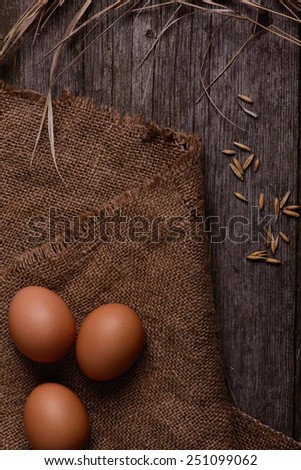 three chicken organic eggs with straw on burlap background