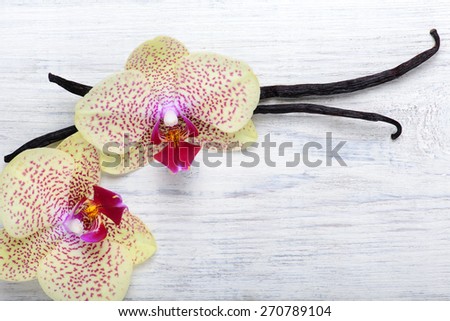 Vanilla pods and orchid flowers on white wooden background with copy space