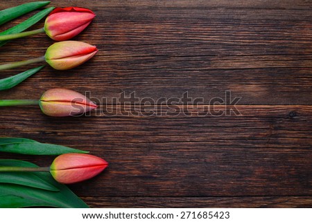 Red tulips flowers bouquet on old wooden table background. Top view with copy space.