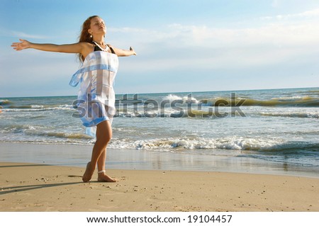 beautiful girl on a sea beach stands and waves hands