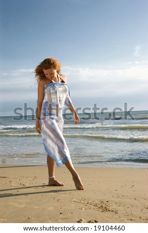 The girl draws by a leg on sand