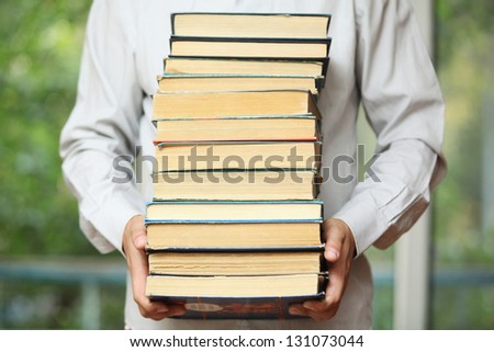 Guy in a shirt holding a stack of old books