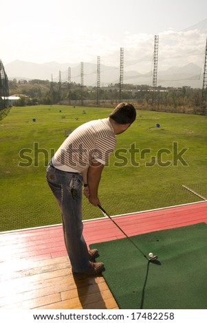 Man training, playing golf on the green