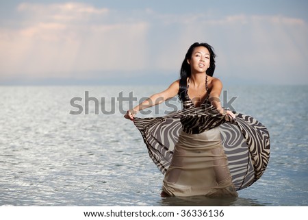 Asian beauty girl stay on the beach in water, play with dress